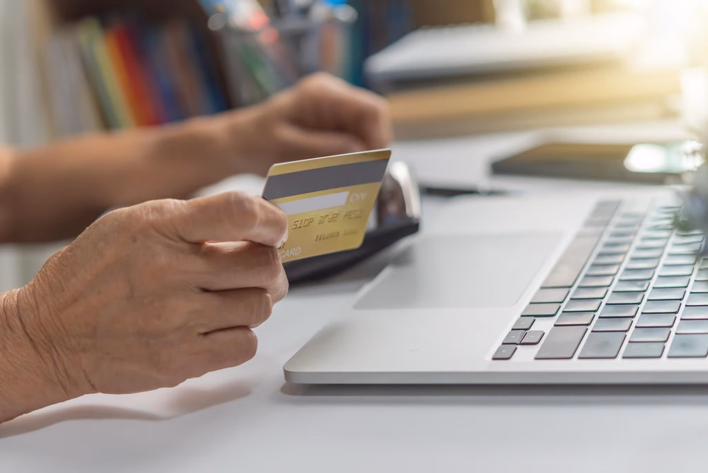 A man about to pay with his credit card at his computer.
